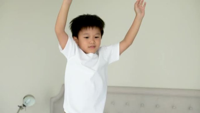 亚洲孩子跳上酒店的卧室。旅游和度假的概念