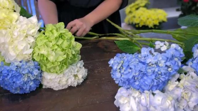 花店妇女在商店里做绣球花花束，双手特写。