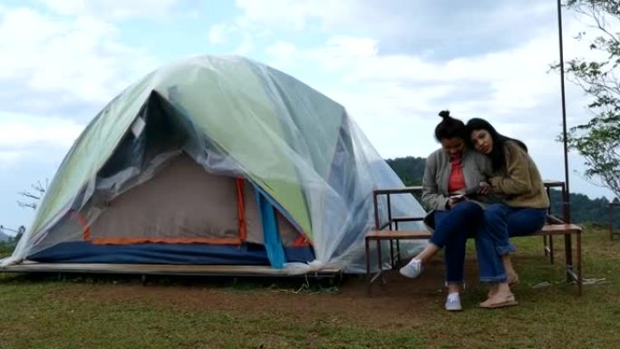 两个亚洲朋友坐在帐篷外的椅子上