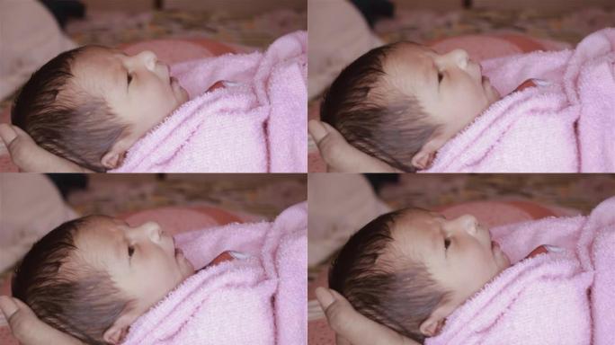 美丽的新生男婴特写镜头 (6天大) 躺在产前医院的妈妈腿上。裹着婴儿毯的孩子 (保暖的衣服) 微笑着