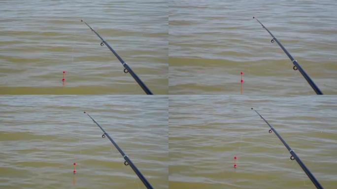 用钓鱼竿钓鱼。用钓线上的钩子漂浮在水面上，在波浪上摆动。从船上看。鱼的诱饵。在夏天的早晨赶上。男人的