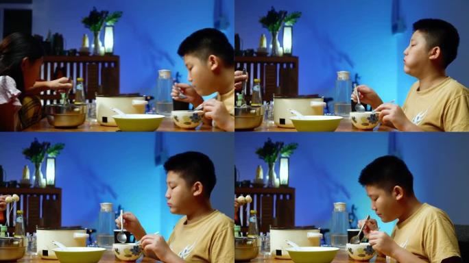 快乐的亚洲男孩吃寿喜烧或sha锅，火锅将食物与家人与led灯混合在一起，生活方式理念。