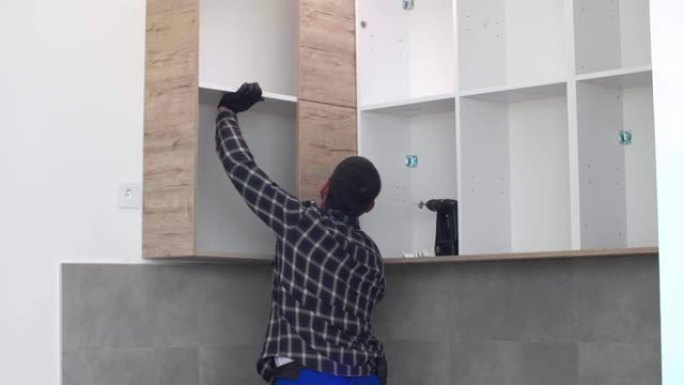 木匠将新组装的厨房架子放在预定的位置。