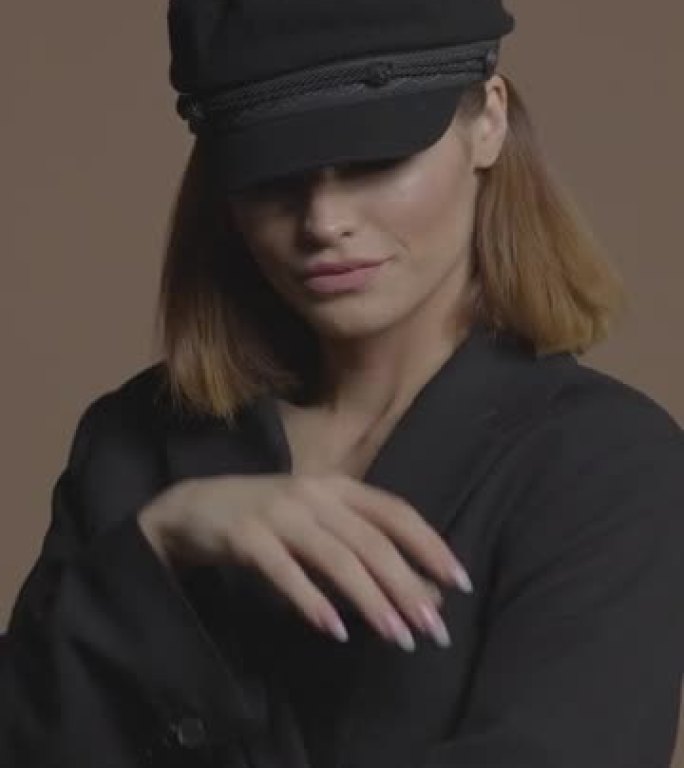 一个美丽的年轻女孩，戴着黑色眼妆，戴着黑色帽子。垂直格式视频