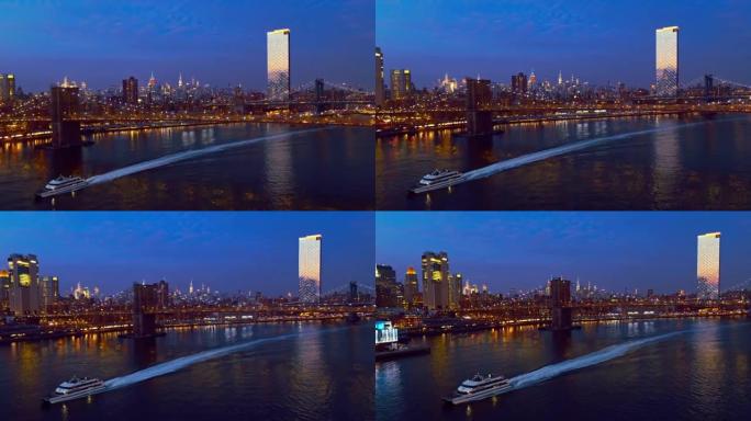 水上渡轮在曼哈顿中城前经过，在夜间照明。带有平移摄像机运动的无人机视频。航拍无人机视频具有向后和向下