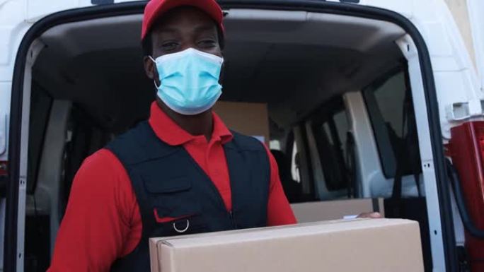 非洲男性快递员用卡车运送包裹，同时佩戴防护面罩以防止冠状病毒