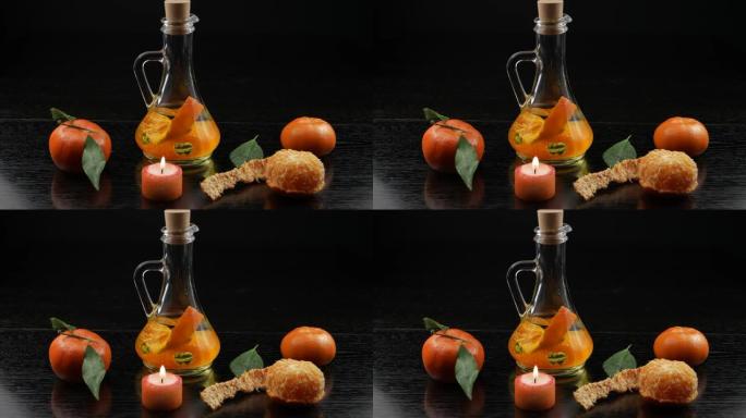 一瓶植物油，在黑色木桌上用橘子，香薰蜡烛和橘子调味