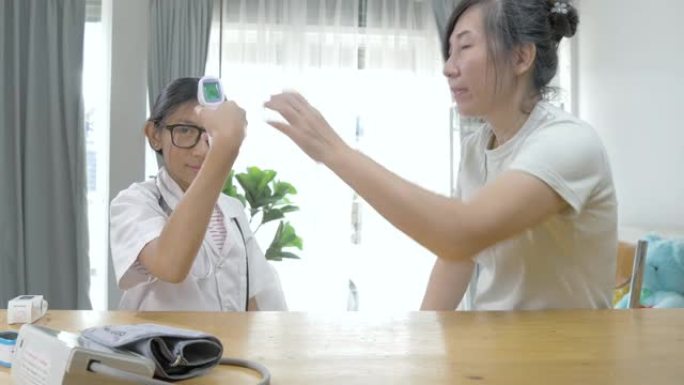 亚洲医生女孩使用红外温度计与病人在家，健康的生活方式理念。