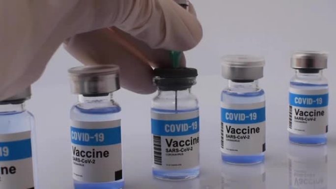 全高清，手持注射器从新型冠状病毒肺炎疫苗瓶中取出蓝色液体疫苗