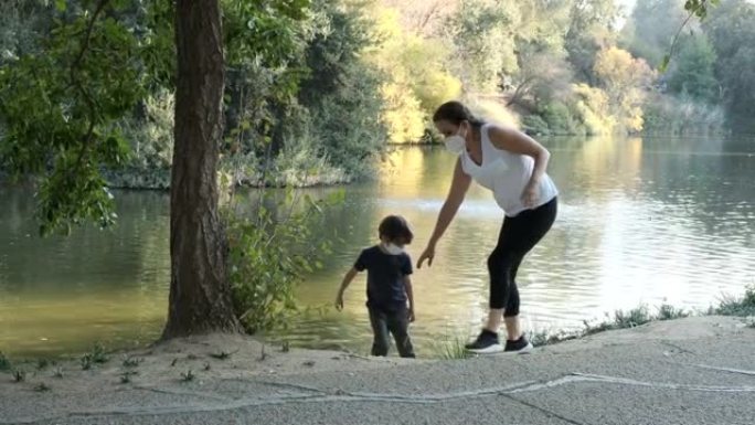 成熟的女人和她的孩子儿子都戴着防护口罩走路