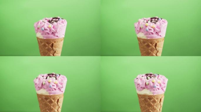 浆果冰淇淋蛋卷，绿底有巧克力片，旋转。五颜六色的糖洒在美味的自制白色和粉红色冰淇淋上。