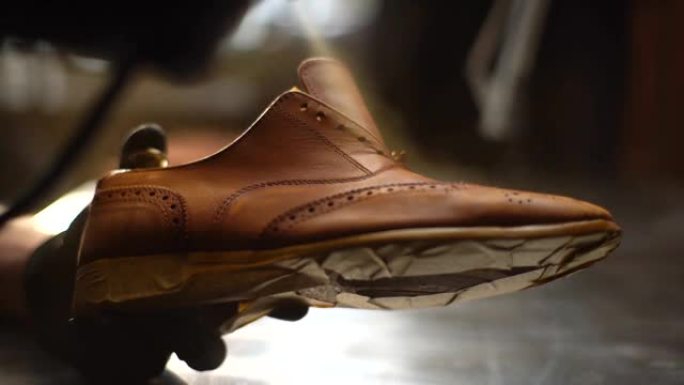 鞋匠的特写镜头在黑色手套上喷涂浅棕色皮鞋的油漆，慢动作。