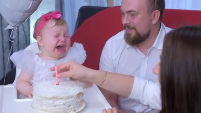 女婴在蛋糕上碰蜡烛在她的第一个生日被烧死并哭泣。