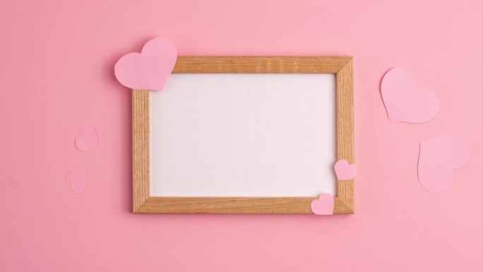 粉红色纸心形的停止运动动画在粉红色背景的木框上及其附近情人节浪漫周年婚礼节日概念平躺着复制空间