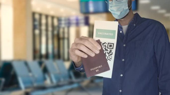 身份不明的男子戴着口罩，持有护照和接种疫苗的绿色通行证证书。