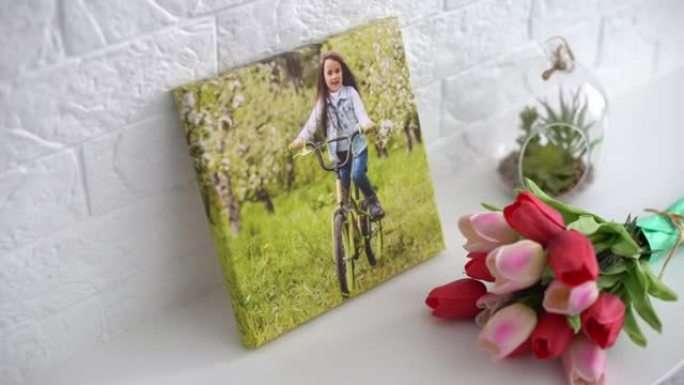 活跃的小女孩和鲜花郁金香的照片画布作为节日礼物躺在架子上