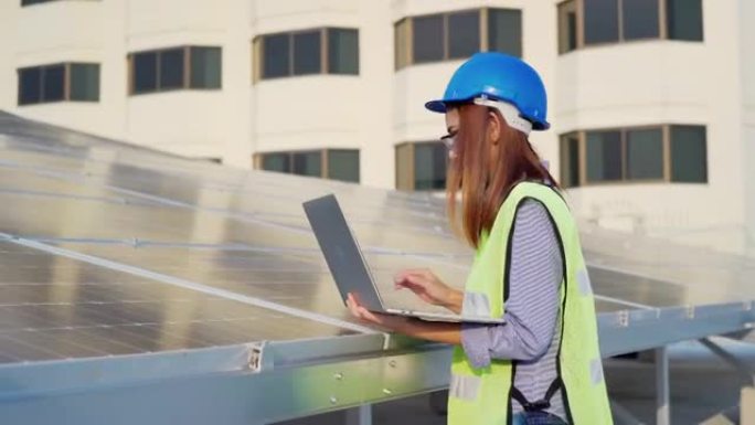 穿着制服的亚洲女工程师在太阳能电池板工厂与笔记本电脑一起工作
