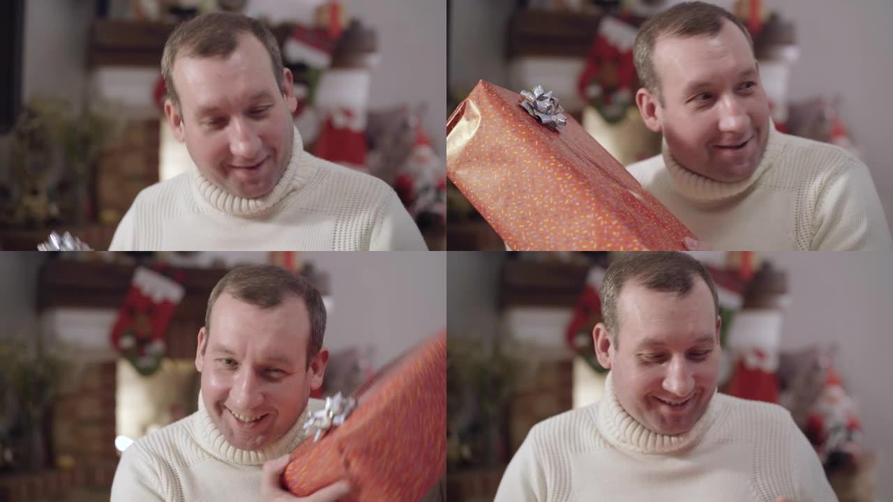 兴奋的成年白人男子摇晃圣诞礼盒微笑的特写肖像。快乐的黑发快乐的家伙在家收到新年礼物。兴奋和庆祝概念