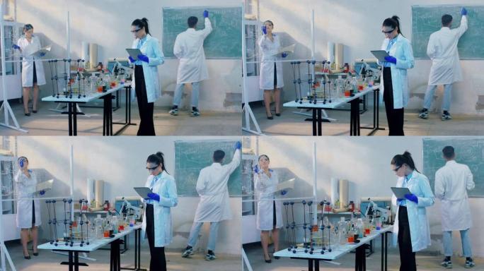在一个化学实验室小组的科学家一起研究抗病毒疫苗，他们分析了各种实验的结果，人在黑板上写了一些化学式。