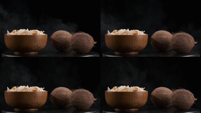 桌子上装满薯条和两个实心椰子的木碗周围冒出白烟。黑色背景