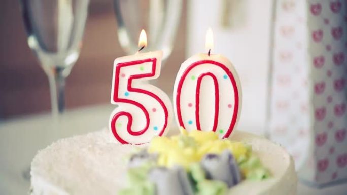 生日蜡烛作为50号50在桌上的甜蛋糕上，50岁生日，调子视频