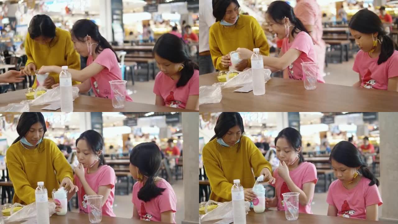快乐的亚洲儿童交谈和分享棉花糖，一些小吃与家庭一起在美食广场，生活方式理念。