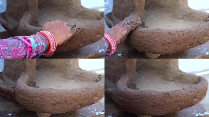 女人用手在陶炉上摩擦湿粘土砂浆。手工泥炉形成。制作粘土炉的传统艺术。