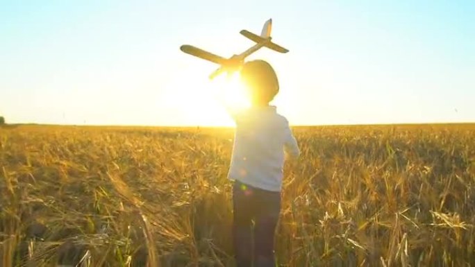 日落时，快乐的小男孩在麦田里用玩具飞机奔跑。孩子在户外夏天玩飞机，小飞行员梦想着飞行旅行度假快乐的家