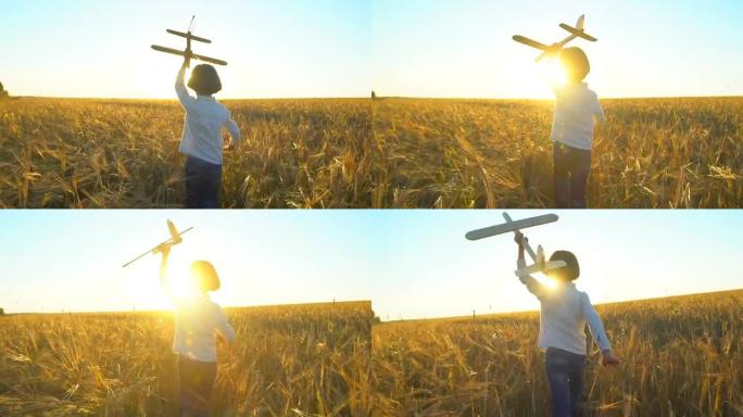 日落时，快乐的小男孩在麦田里用玩具飞机奔跑。孩子在户外夏天玩飞机，小飞行员梦想着飞行旅行度假快乐的家