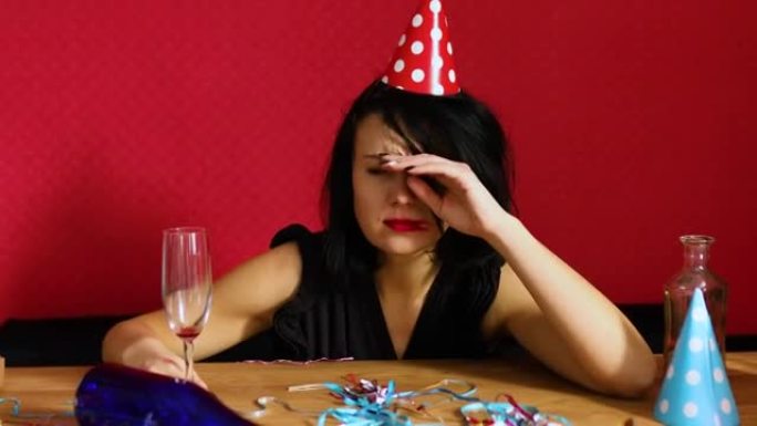 生日派对结束后，戴着红色擦口红和帽子的年轻女子早上在凌乱的房间里的桌子上醒来