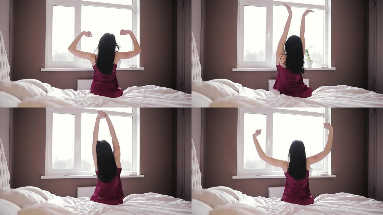 穿着红色睡衣的黑发女孩醒来后在床上伸展，向后看，进入一个快乐而放松的一天后，睡个好觉。美梦，早上好，
