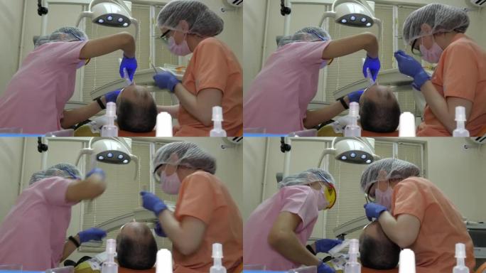 一名牙医和一名助手正在治疗一个人的牙齿。