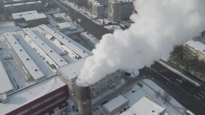 污染的镜头。白烟来自位于大城市中心的一个巨大的工业工厂烟囱，周围有居民区。