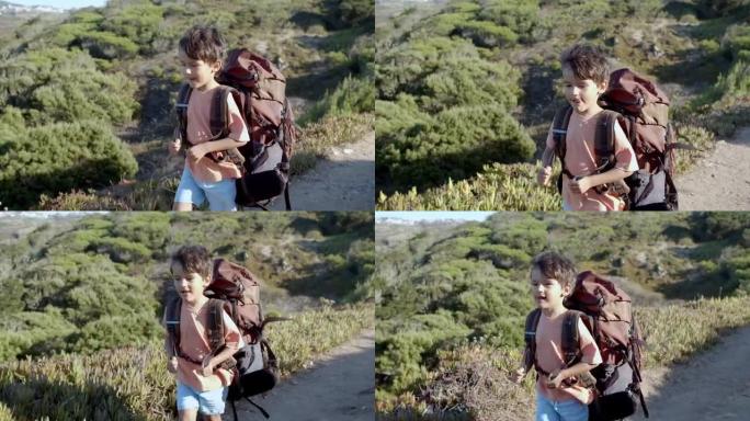 可爱的男孩走在山路上，背着大背包