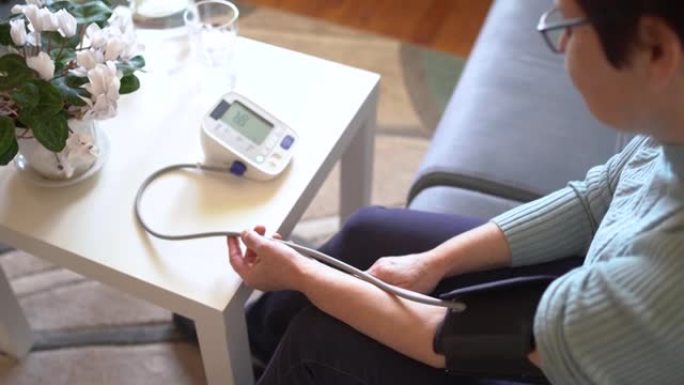 高级妇女在家中测量血压