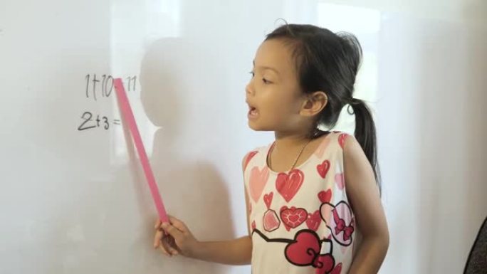 快乐的亚洲女孩在家上学期间在白板上写数学科目的问题和答案，呆在家里的概念。