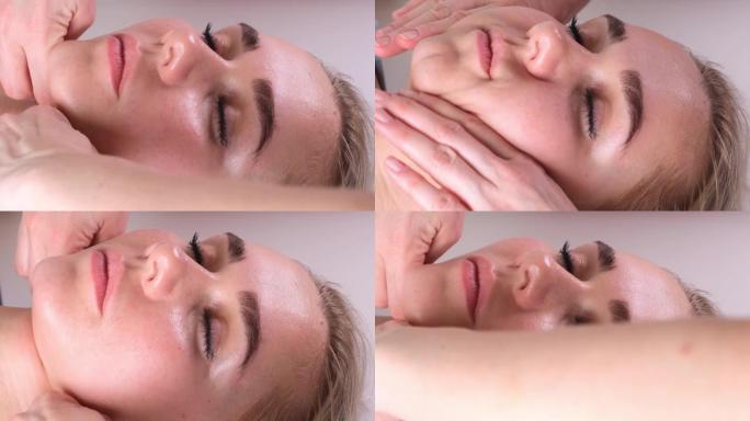 面部按摩美容治疗。特写一名年轻女子的脸躺在背上，得到瘦脸按摩，捏和滚动技术
