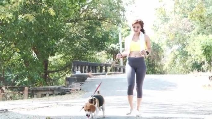 年轻的亚洲妇女在夏天和她的狗在公园里锻炼。