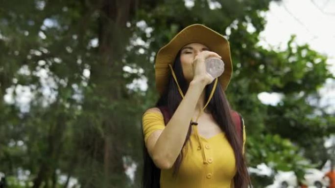 女游客在阳光明媚的夏日在森林里喝水。
