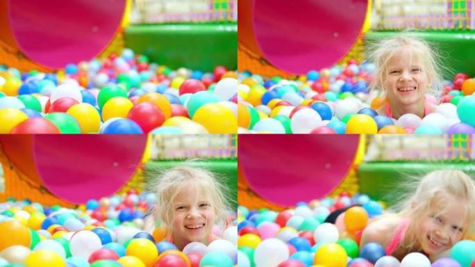 在游戏室玩得开心。金发女孩在室内操场上玩耍，躲在游戏中心大干戏水池里的多色塑料球里。休闲活动