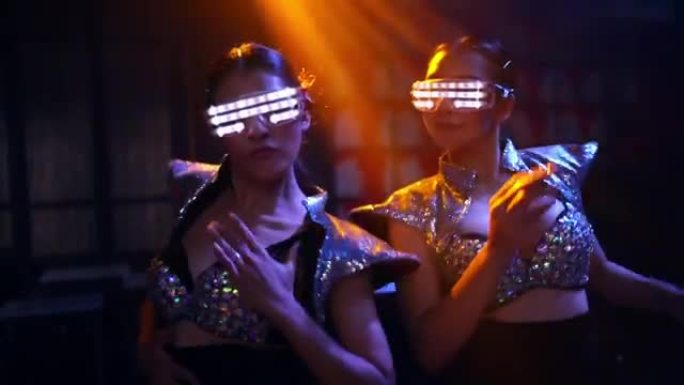 在夜总会，两个自信的女人戴着发光的眼镜，随着电子音乐跳舞。