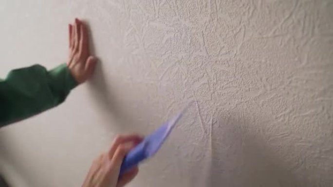 在新公寓里贴墙纸。粘合后对齐墙纸。正在修理的女人。