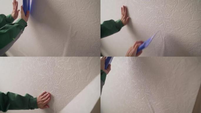 在新公寓里贴墙纸。粘合后对齐墙纸。正在修理的女人。