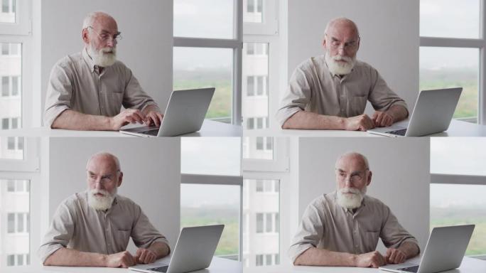 年迈的灰色大胡子的祖父在笔记本电脑上工作，试图应付艰巨的任务