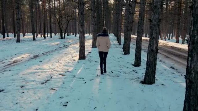 迷人的年轻美女冬天走在白雪皑皑的森林和留下的脚印