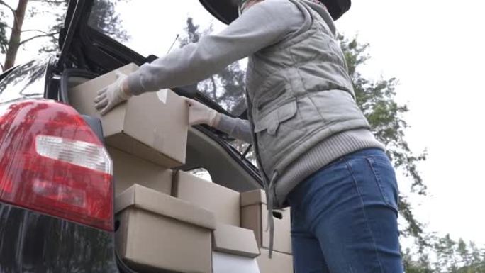 一名穿着防护服的志愿者将箱子装入汽车后备箱