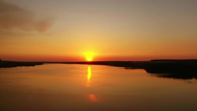 水面上令人惊叹的日落。夕阳下的橙色背景。晚上，黄金之路在河上反射。