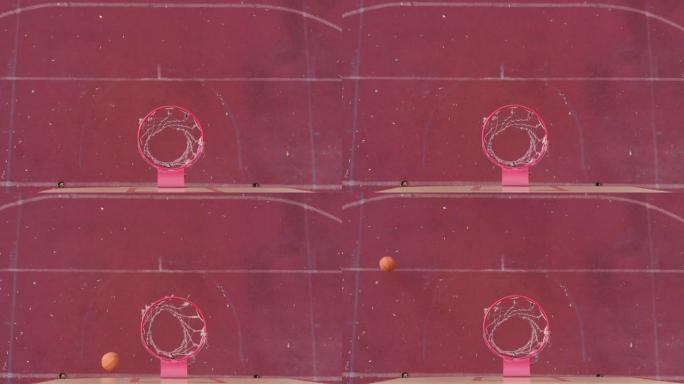 篮球篮板上方的高顶角橙色球干净地击中篮筐并在室外球场得分