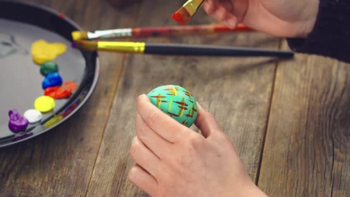 木制背景上复活节彩蛋上女性绘画的特写。基督教节日用天然颜料染色鸡蛋