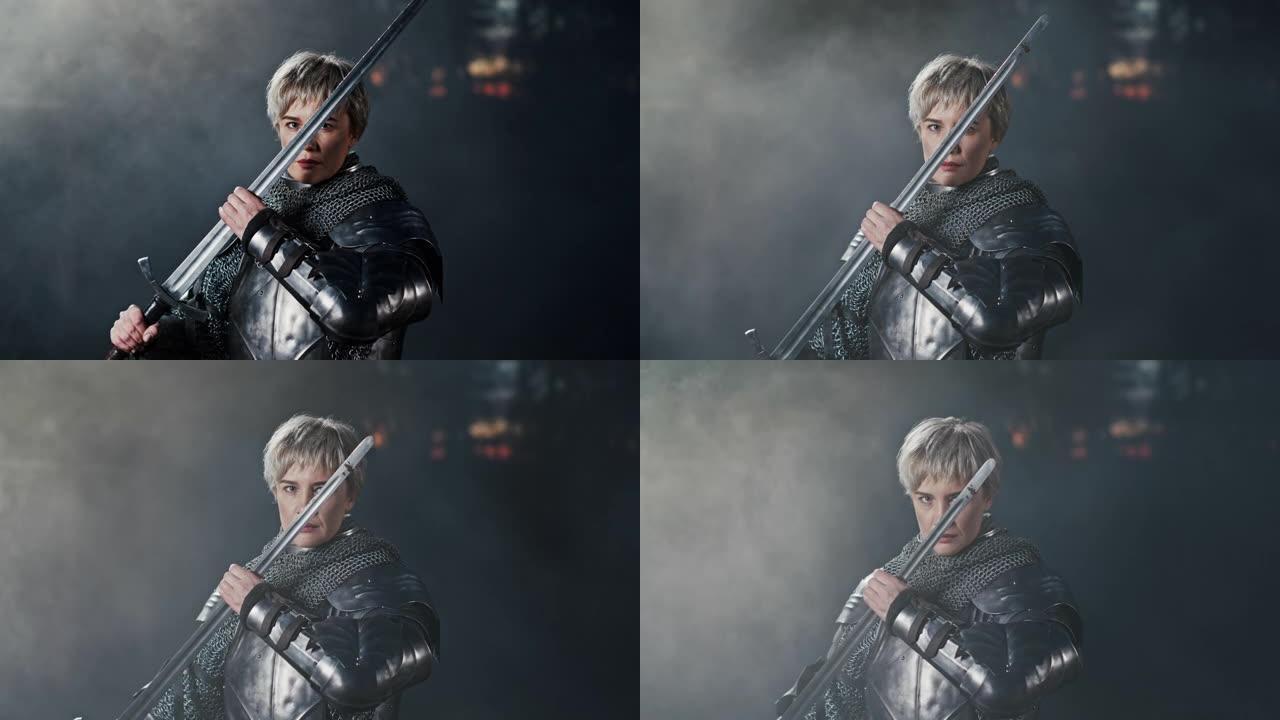 一个女人穿着金属中世纪战士盔甲的戏剧性镜头，用剑检查刀片，同时站在黑暗的环境中，背景是烟雾